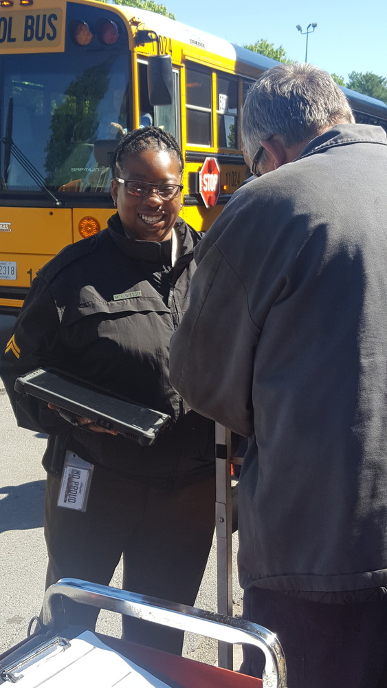 Vehicle Compliance Agent Mashelia Gibson using handheld tablet to input bus inspection information